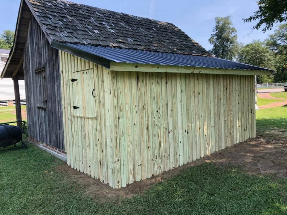 Restored shed with new pressure-treated board siding and metal roof