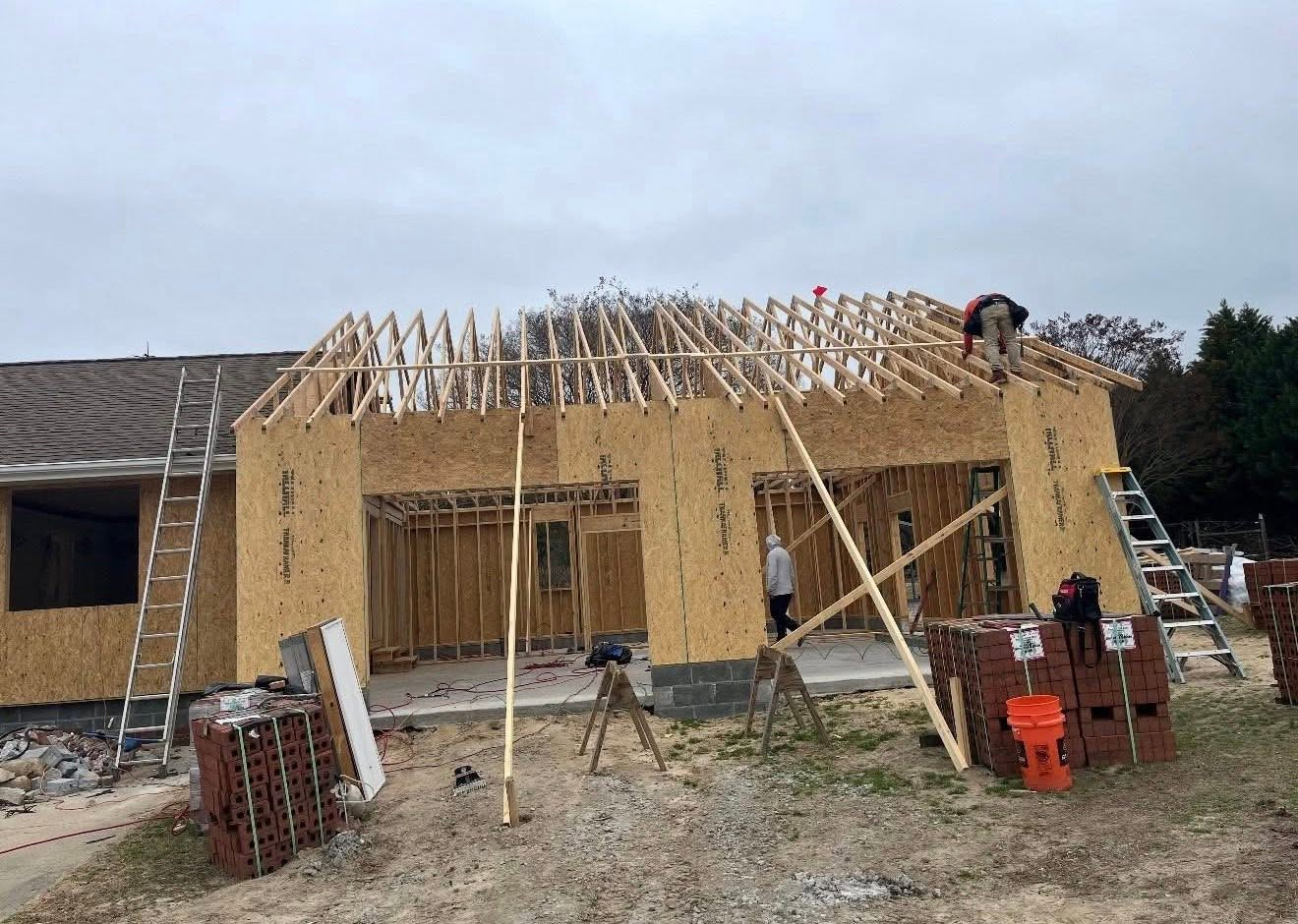 Garage addition under construction with wall sheathing and roof framing in progress