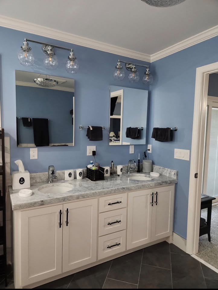 Finished bathroom with double vanity, marble-look countertop, and blue walls