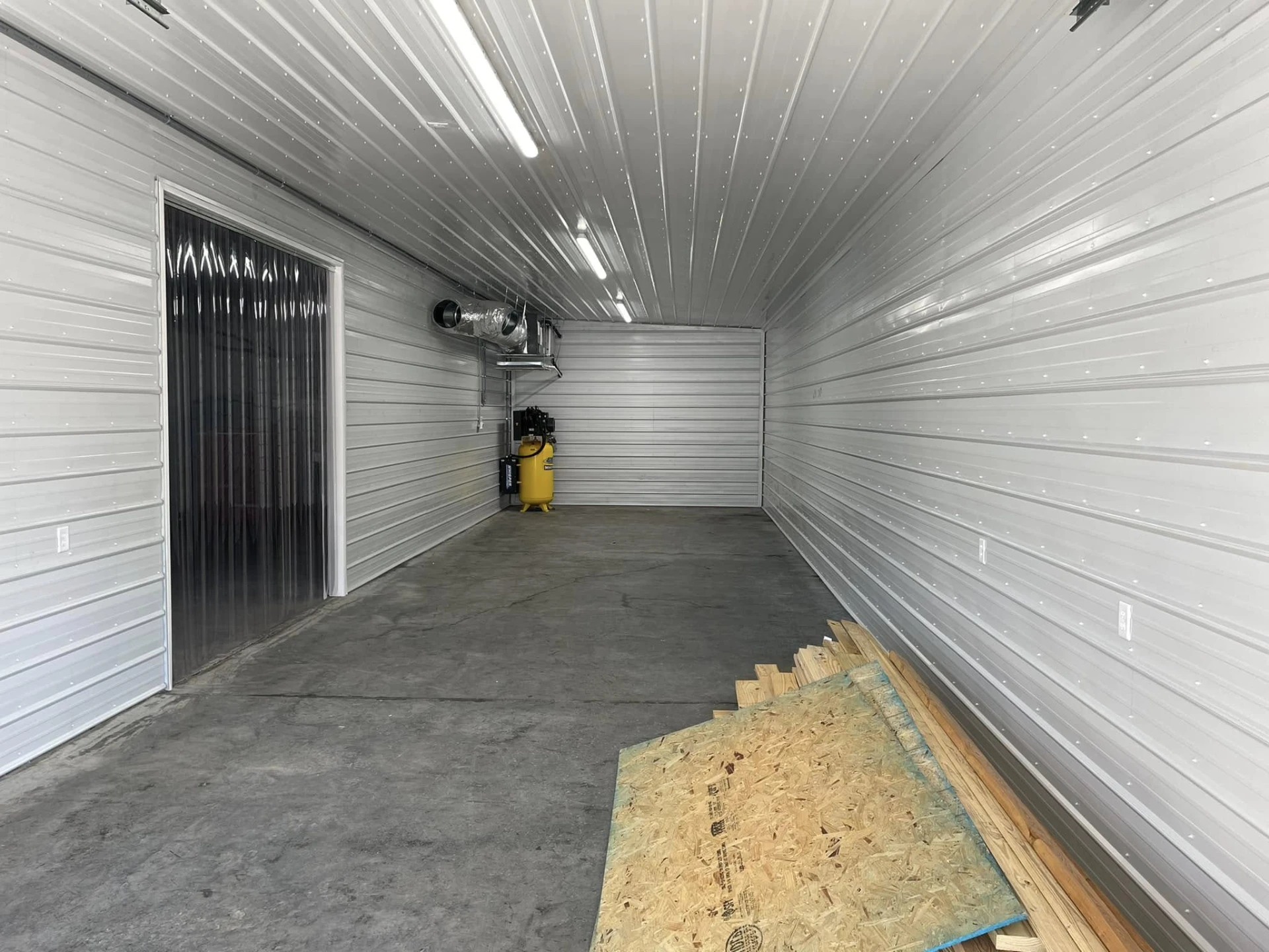 Finished workshop interior with metal wall panels, lighting, and concrete floor