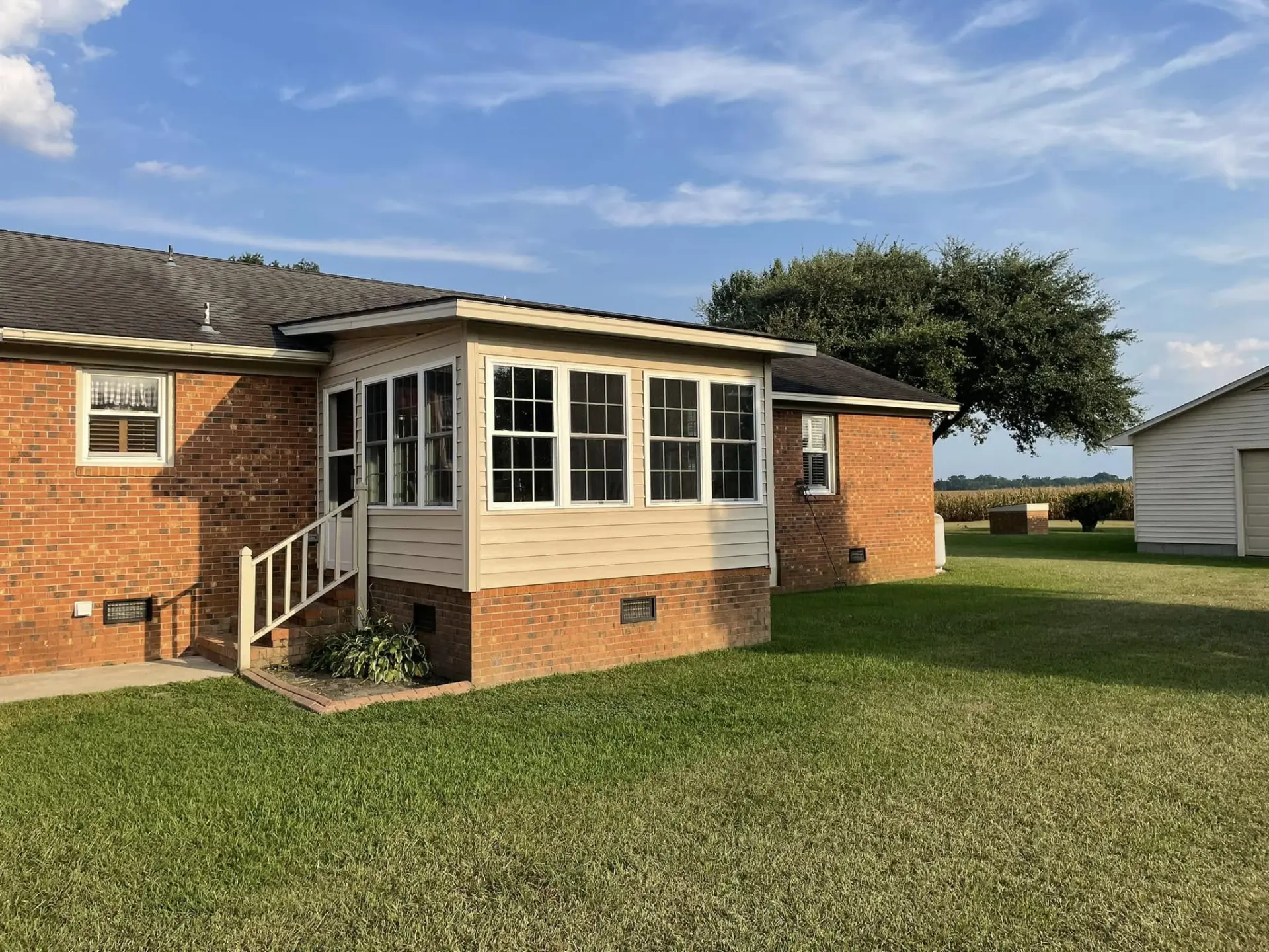 Completed enclosed porch addition with large windows and finished siding