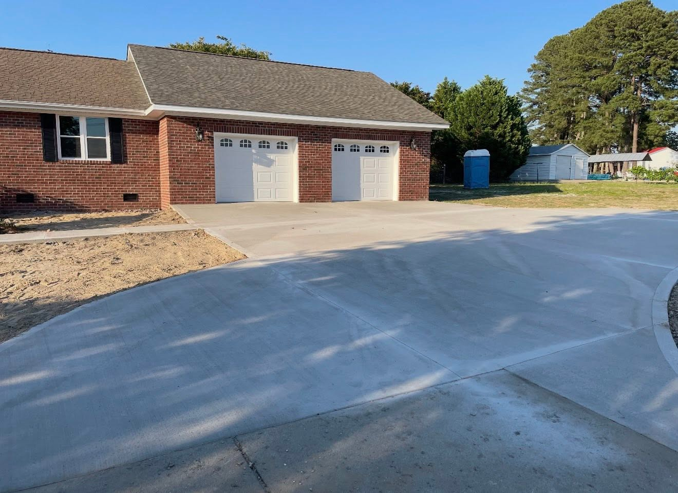 New concrete driveway and two-car garage apron at a brick home