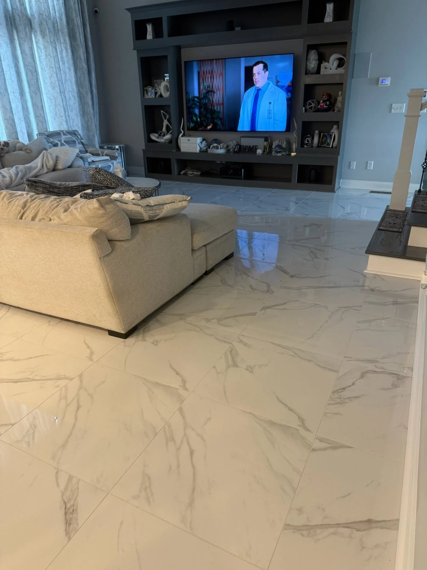 Remodeled living room with large-format marble-look tile flooring and built-in media wall
